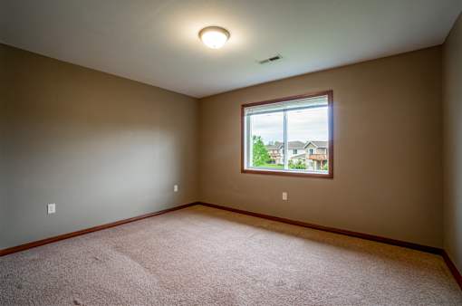 A room with a window and a carpeted floor.