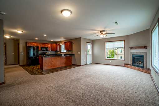 A spacious living room with a fireplace and a kitchen area in the background.
