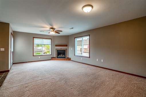 A living room with a fireplace and a ceiling fan.