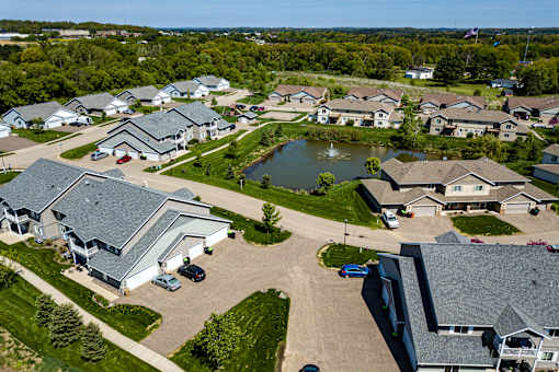 A bird's eye view of a residential neighborhood with houses and a pond.