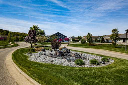 A residential area with a well-maintained lawn and a rock garden.