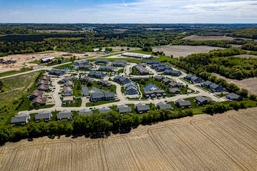 A bird's eye view of a residential area with houses and a large open field.
