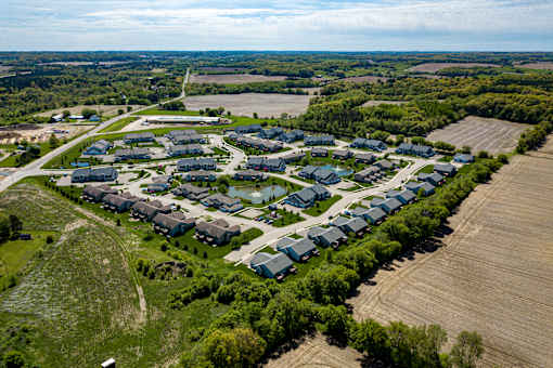 A bird's eye view of a residential area with houses surrounded by greenery and a parking lot.