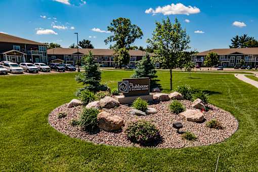 A landscaped area with a sign that reads "25 Clubhouse" in front of a building.