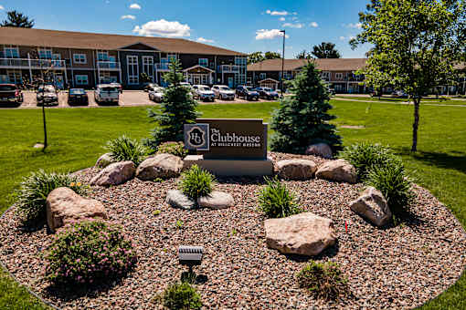A landscaped area with a sign that says "Clubhouse" in front of a building.