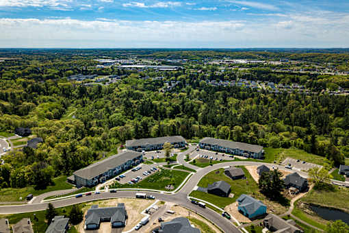 A bird's eye view of a residential area with houses and a large building surrounded by trees.