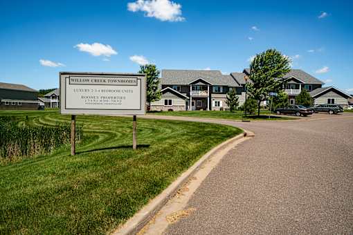 A sign for Willow Creek Townhomes stands in front of a building.