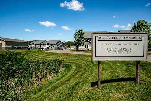 A sign for Willow Creek Townhomes is in front of a grassy area.