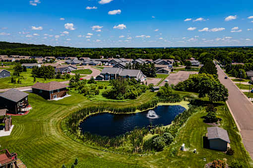 A bird's eye view of a residential area with houses and a pond.