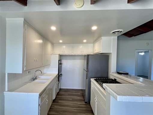 A kitchen with white cabinets and a black refrigerator.