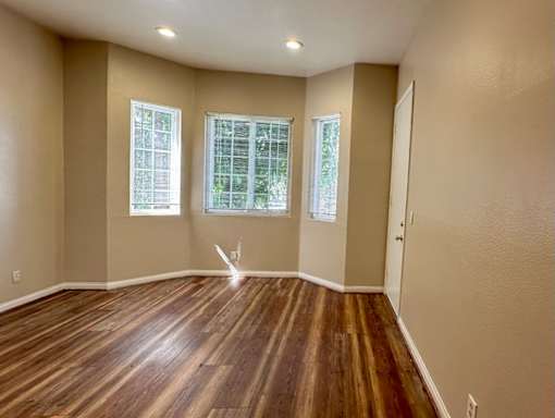 A room with wooden floors and two windows.