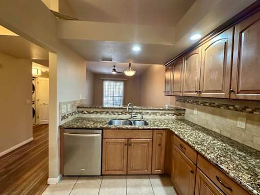 A kitchen with granite countertops and wooden cabinets.