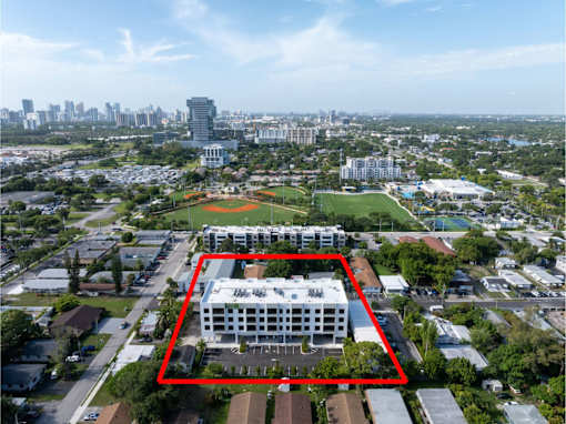 A large white building with a red square around it is in the middle of a city.