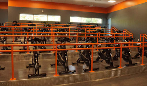 A gym with orange railing and exercise bikes.