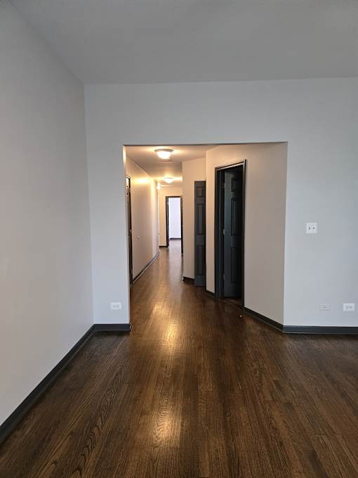 A long hallway with wood floors and white walls.