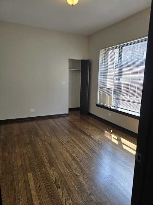 A room with wooden floors and a window with blinds.