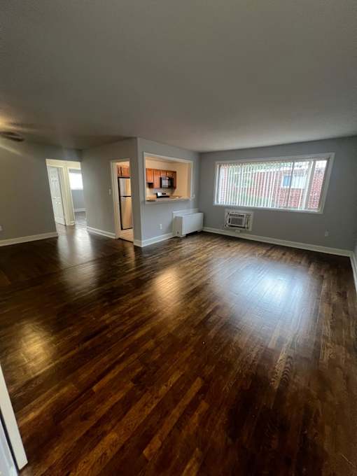 A room with wooden flooring and a window with blinds.
