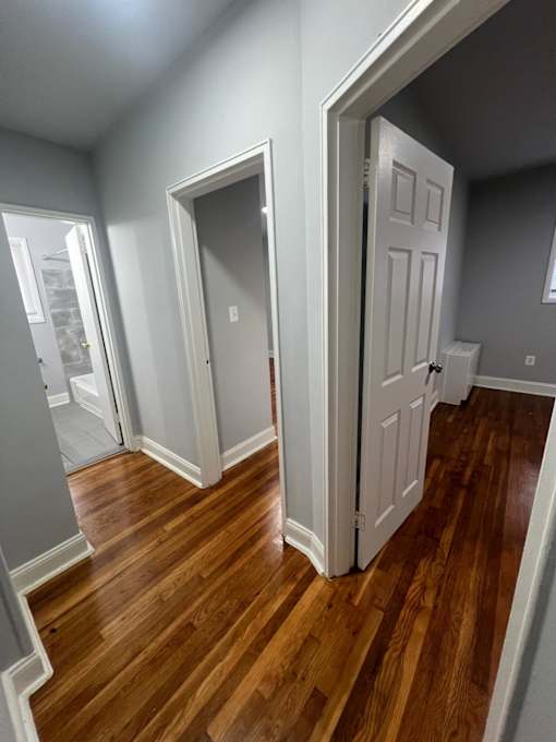 A room with a white door and wooden floors.