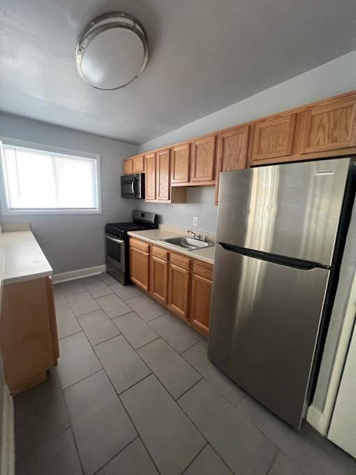 A kitchen with wooden cabinets and a stainless steel refrigerator.
