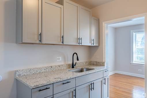 A kitchen with a granite countertop and white cabinets.