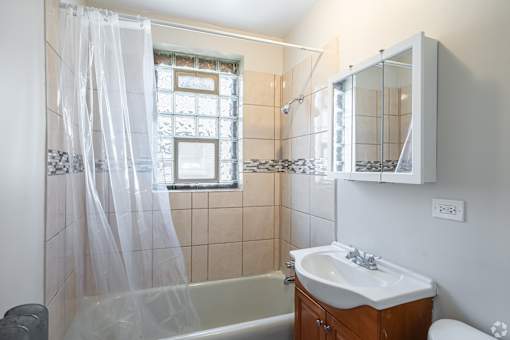 A bathroom with a white shower curtain and a brown vanity.