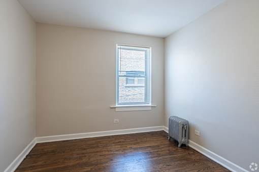 A room with a window and a heater on the floor.