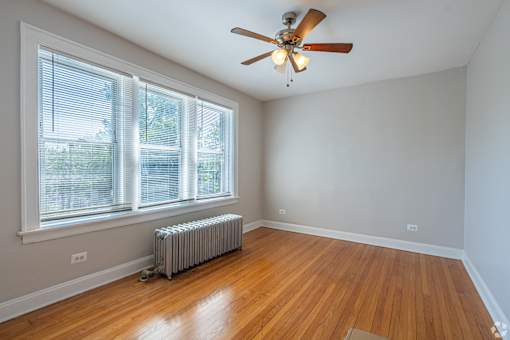 A room with a ceiling fan and a radiator on the floor.