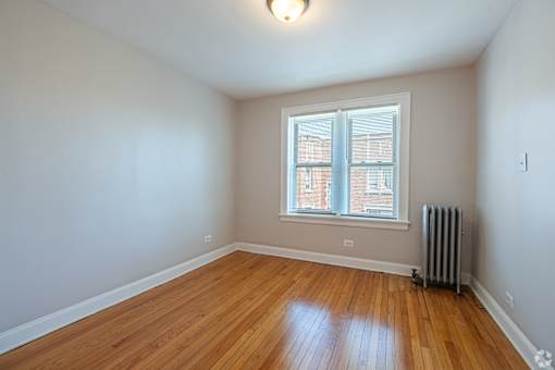 A room with a window and a radiator on the floor.