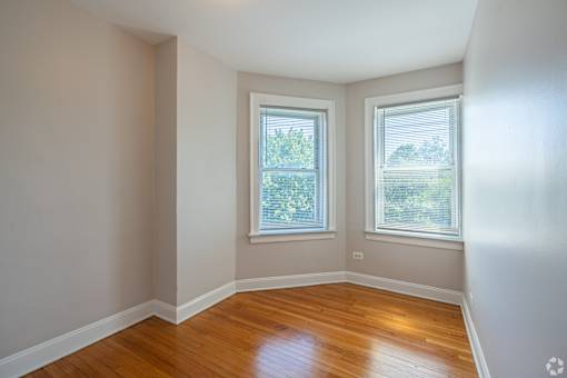 A room with wooden floors and two windows.