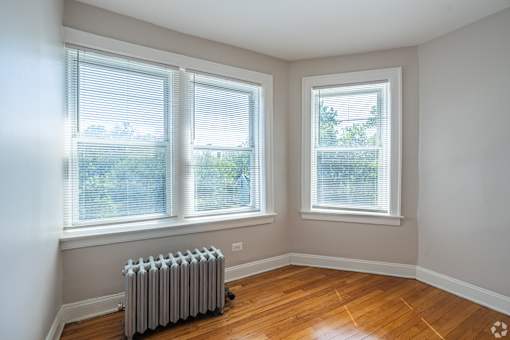 A room with a radiator and two windows.