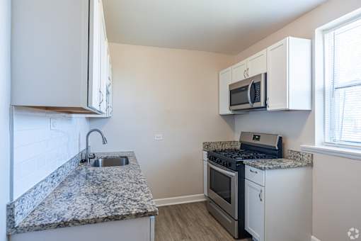 A kitchen with granite countertops and white cabinets.