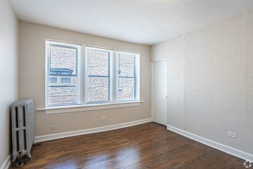 A room with a window and a radiator on the floor.