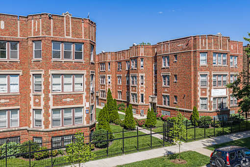 A red brick building with a black fence in front.