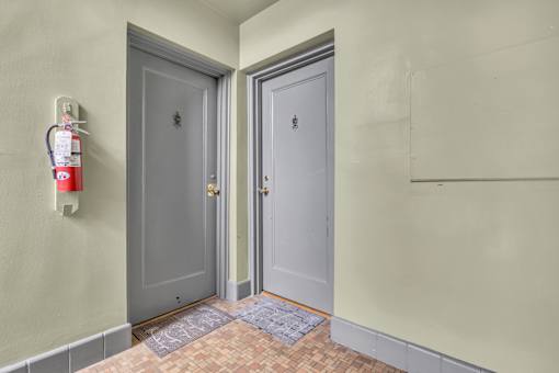 A hallway with two doors and a fire extinguisher on the wall.