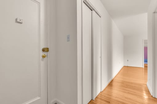 A hallway with a white door and a gold doorknob.
