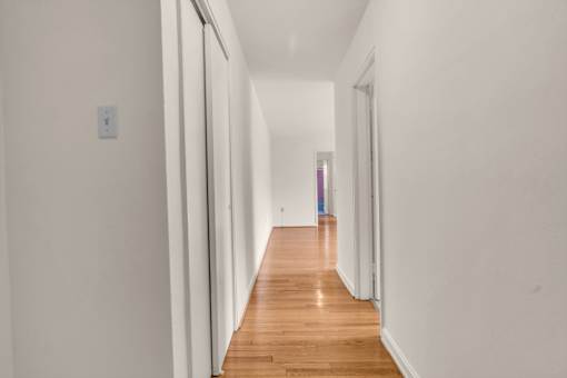 A long hallway with white walls and wood floors.
