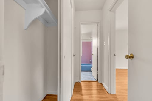 A hallway with a white door and a gold doorknob.