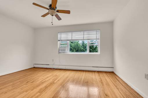 A room with a ceiling fan and a window with blinds.