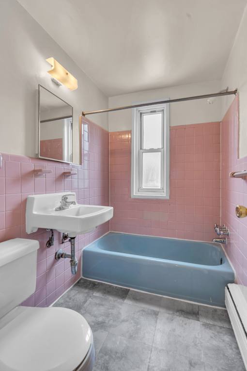 A pink bathroom with a blue tub and a white sink.