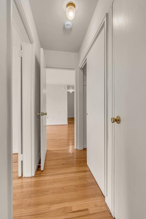 A long hallway with doors on both sides and a light on the ceiling.