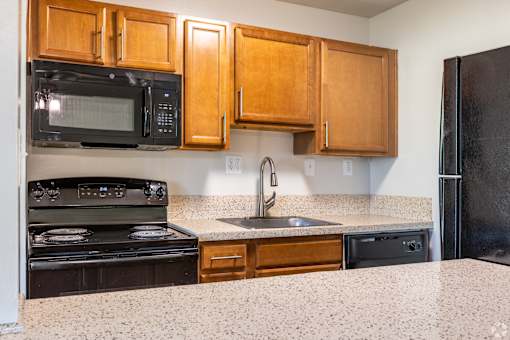 A kitchen with black appliances and wooden cabinets.