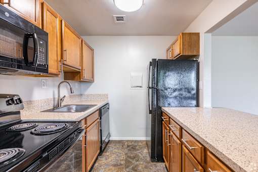 A kitchen with black appliances and wooden cabinets.