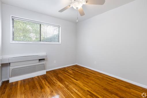 A room with a ceiling fan and a window with blinds.