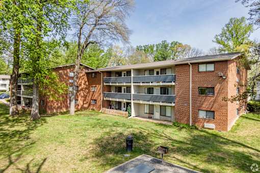A red brick apartment building with a green lawn in front.