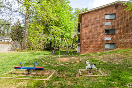 A playground with a swing set and a seesaw in a yard.