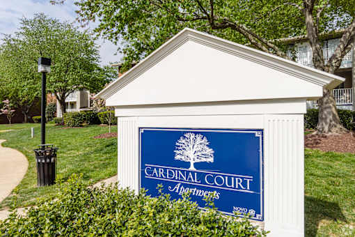 A sign for Cardinal Court Apartments is displayed in front of a building.