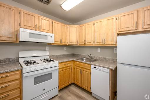 A kitchen with wooden cabinets and a white stove.