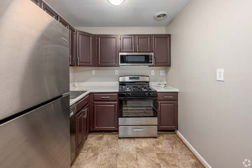 A kitchen with brown cabinets and a stainless steel refrigerator.