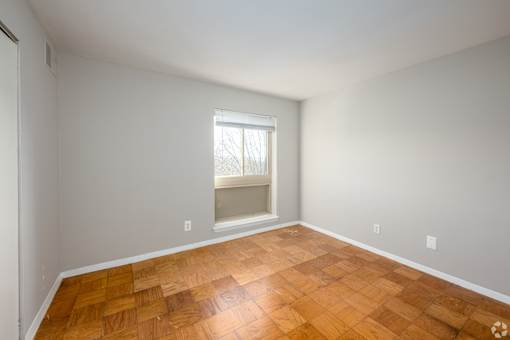 A room with wooden flooring and a window.