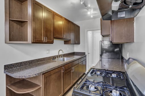 a kitchen with wood cabinets and granite counter tops and a stove top oven and sink
